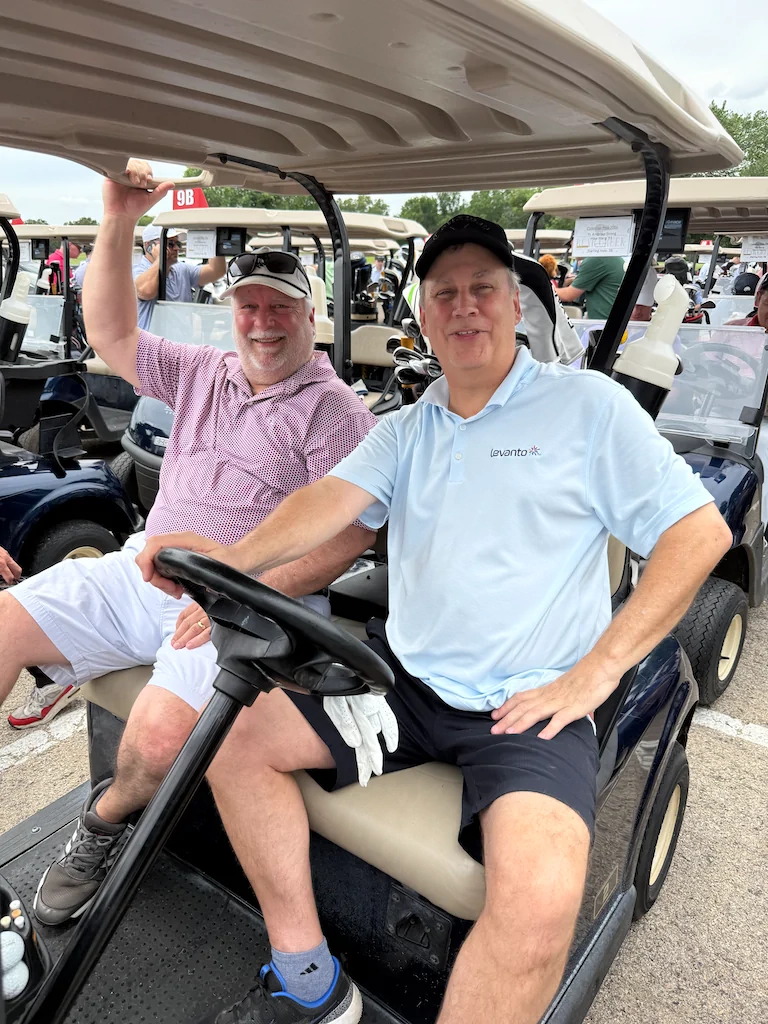 Alumni participants riding in a golf cart on the course