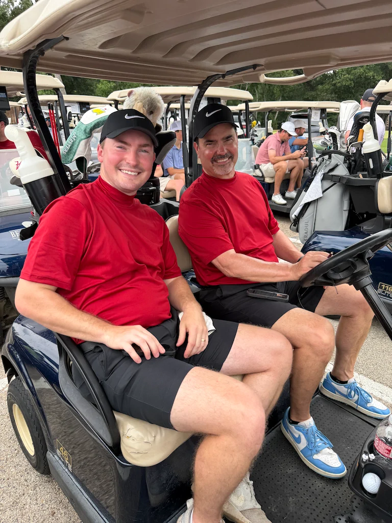 Golf tournament participants riding in a golf cart
