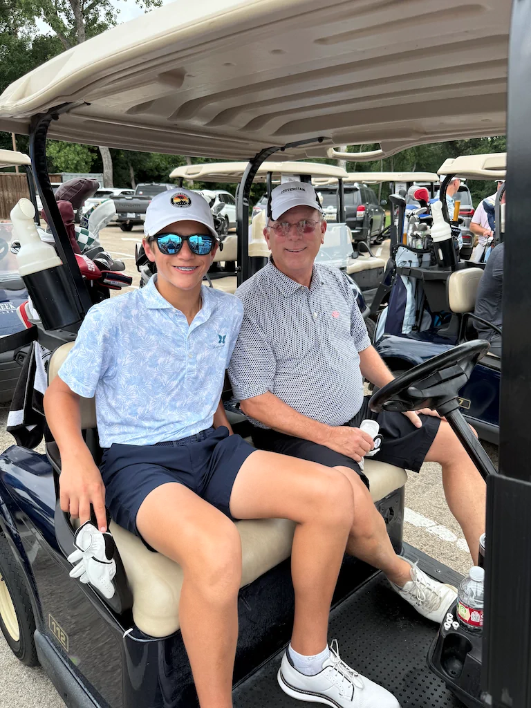Golfers riding in a golf cart before tournament play